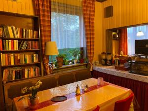 a dining room with a table and a book shelf at Pension Waldblick in Spiegelau
