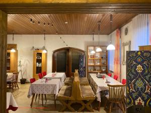 a dining room with two tables and red chairs at Pension Waldblick in Spiegelau