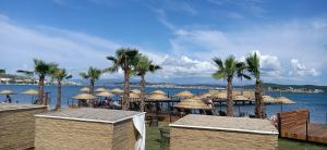 a group of straw umbrellas and palm trees on a beach at Cunda Fora Glamping in Ayvalık