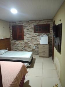 a room with two beds and a brick wall at Pousada Recanto das Fontes in Beberibe
