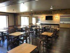 a restaurant with wooden tables and chairs and a flat screen tv at Clubhouse Inn in West Yellowstone
