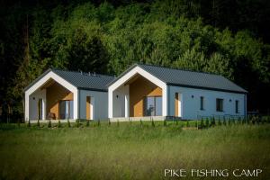 two white houses with black roofs in a field at Pike Fishing Camp in Nadole