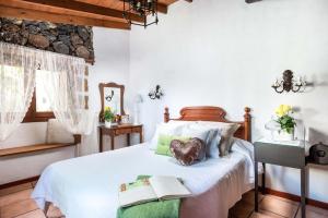 a bedroom with a bed with a book on it at Romantic Hamlet Cottage with Private Pool La Fragua de Eliseo in Candelaria