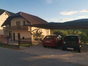 two cars parked in a parking lot in front of a house at Apartman Nika in Otočac