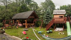 a playground with a play structure and a wooden house at Sieraton Pokoje i Apartament in Stronie Śląskie