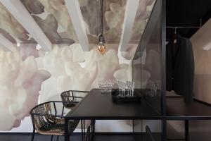 Casa Trentini - Atemporary Art Apartments في ترينتو: غرفة طعام مع طاولة وكراسي على الحائط