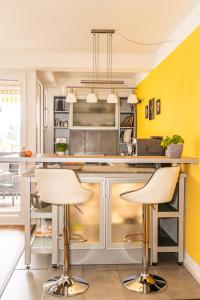 eine Küche mit gelben Wänden und Barhockern in der Unterkunft Ein Zimmer Apartment Bernau mit großer Garage incl in Bernau am Chiemsee