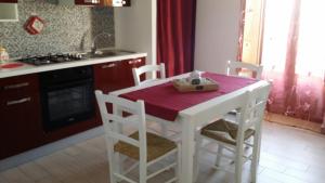 cocina con mesa blanca con sillas y fregadero en DEA DEL BORGO, en SantʼAmbrogio