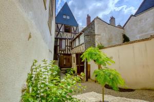 a courtyard of an old house with a palm tree at Le cocon Bourbonnoux in Bourges