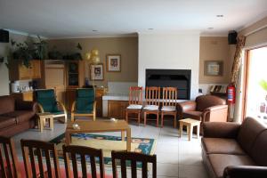 uma sala de estar com um sofá, uma mesa e cadeiras em Old Oak Guest House em Bellville