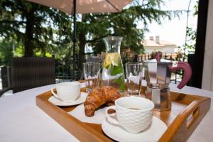 a tray with coffee cups and croissants on a table at Apartment Amalia Volosko in Opatija
