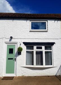 ein weißes Haus mit einer grünen Tür und einem Fenster in der Unterkunft Ladybird Cottage, Dog Friendly, Couples or Small families, Yorkshire Wolds - Countryside and Coast in Great Driffield