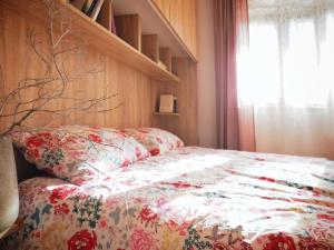 a bed with a floral comforter and a window at Lo scoiattolo in Cave
