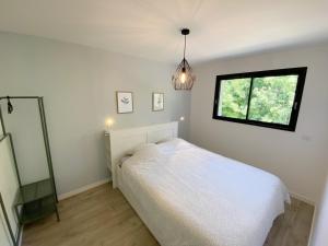 een slaapkamer met een wit bed en een raam bij Aux Peupliers de Pradian - Aurora in Bassens