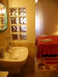 La salle de bains est pourvue d'un lavabo et d'une table rouge. dans l'établissement Pà Blanc B&B, à Alghero