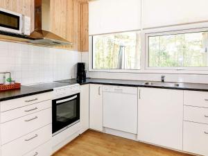 een keuken met witte kasten, een wastafel en een raam bij Holiday Home Kongeørnen in Odde