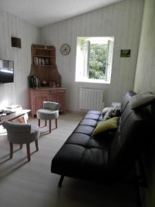 uma sala de estar com um sofá de couro preto e uma janela em Au pré du Mignon aux portes du Marais Poitevin em Thorigny