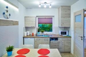 a kitchen with wooden cabinets and a table and a window at Domki Ancora - komfortowe domki nad morzem in Jastrzębia Góra