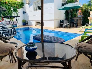 a swimming pool with a glass table and a vase at Au Cœur Des Plages de Rabat in Oulad Kerroum