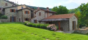 een oud stenen huis met een groen gazon bij Podere Verdi Colline in Poppi