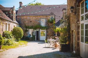 un homme assis à une table avec un chien devant une maison dans l'établissement Le gîte d'Etienne, à Joué-du-Bois