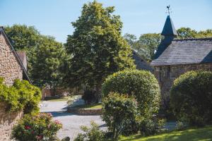 a garden with a church and trees and bushes at Le gîte d'Etienne in Joué-du-Bois