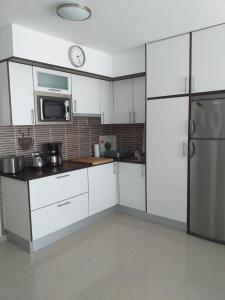 a kitchen with white cabinets and a clock on the wall at Casa Kristin (WLAN gratis) in Costa Calma