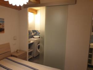 a bedroom with a bed and a bathroom with a washing machine at Villa Oneiro Fronte Mare in Santa Maria Del Focallo