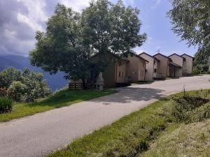 une rangée de maisons sur une route avec un arbre dans l'établissement Chalets "les gentianes", à Sorgeat