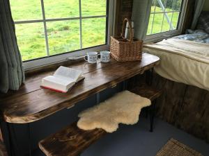 una mesa con dos libros y dos tazas y una ventana en Belan Bluebell Woods Shepherds Hut en Llanidloes