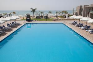 ein großer blauer Pool mit Stühlen und Sonnenschirmen in der Unterkunft Elite Residence & Aqua Park in Ain Suchna