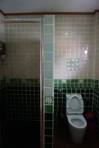 a bathroom with a toilet and green and pink tiles at Oriental Beach By Winnie in Cha Am