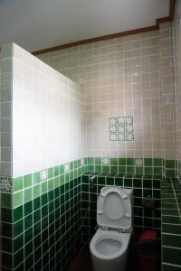 a green and white tiled bathroom with a toilet at Oriental Beach By Winnie in Cha Am