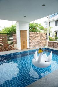 a pool with a inflatable swan in the water at Oriental Beach By Winnie in Cha Am