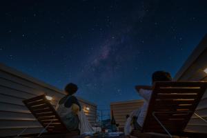 two people sitting on chairs looking at the night sky at HOUS-AGALonomichi in Onomichi