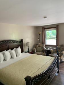 a bedroom with a bed and two chairs and a window at Stay Berkshires in Williamstown