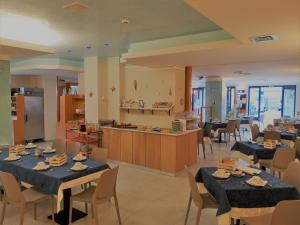 ein Esszimmer mit Tischen und Stühlen sowie eine Küche in der Unterkunft Hotel Tognon in Grado
