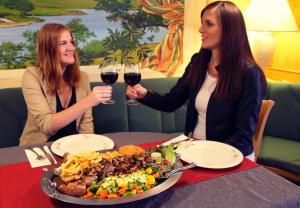 zwei Frauen sitzen an einem Tisch mit einem Teller Essen in der Unterkunft Hotel Igelstadt in Fürstenberg