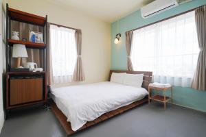 a bedroom with a bed and two windows at Adan hotel in Nago
