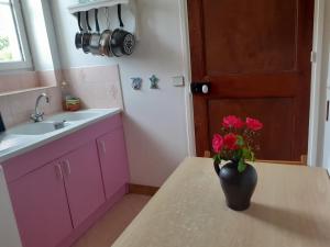eine lila Küche mit einer Blumenvase auf dem Tisch in der Unterkunft Maison Normande in Asnelles