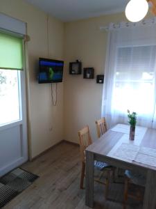 a dining room with a table and a television on the wall at Apartments Zaton Draga in Zaton