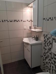 a white bathroom with a sink and a mirror at Apartments Ružica in Zaostrog
