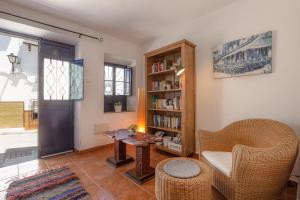 ein Wohnzimmer mit einem Stuhl und einem Bücherregal in der Unterkunft Casa Randonneur, traditional townhouse in Álora. in Alora