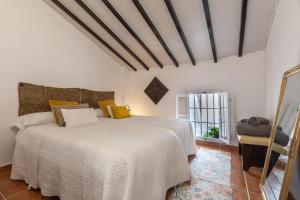 a bedroom with a white bed and a window at Casa Randonneur, traditional townhouse in Álora. in Alora
