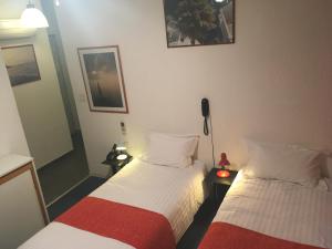 - une chambre avec 2 lits et un téléphone sur une table dans l'établissement Arche Hotel, à Vierzon