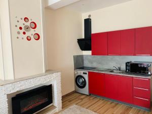 une cuisine avec des placards rouges et une cheminée dans l'établissement Splendide Studio au cœur historique de Fréjus, à Fréjus