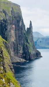 a large cliff overseeing a body of water at The Atlantic view guest house, Sandavagur, Faroe Islands in Sandavágur