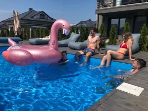 a group of people sitting in a pool with a pink swan at Rainbow Palanga in Palanga