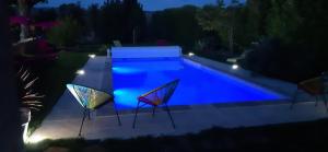 uma piscina com duas cadeiras ao lado à noite em La Clé Des Champs em Chabeuil