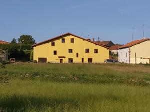 ein gelbes Haus auf einem Grasfeld in der Unterkunft Casa Rural Valle de Altamira in Santillana del Mar